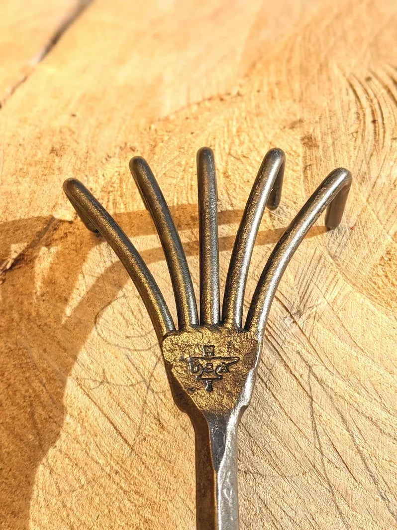 Crow's Foot Garden Tool, Hand Forged "The Claw" close up of tool head with child's drawing on wooden background.