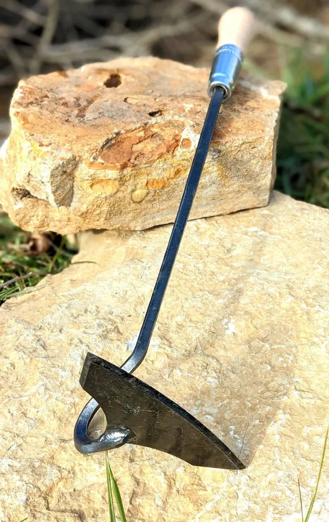 Batwing hand forged garden tool by Homestead Iron full image on stone. 