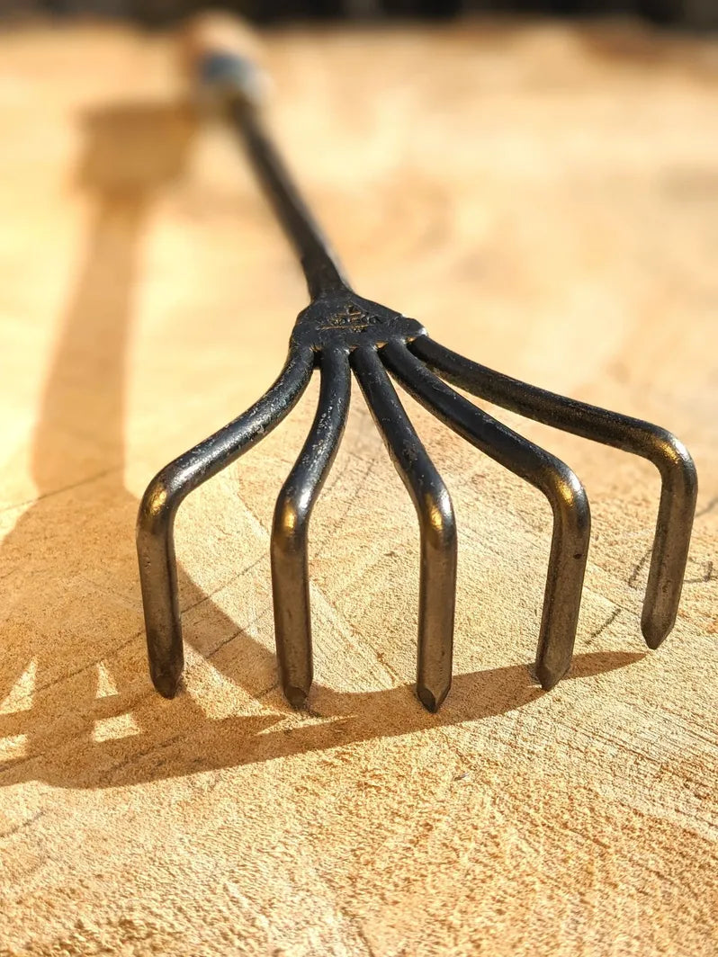 Crow's Foot Garden Tool, Hand Forged "The Claw". Close up of tool head on wooden background. 