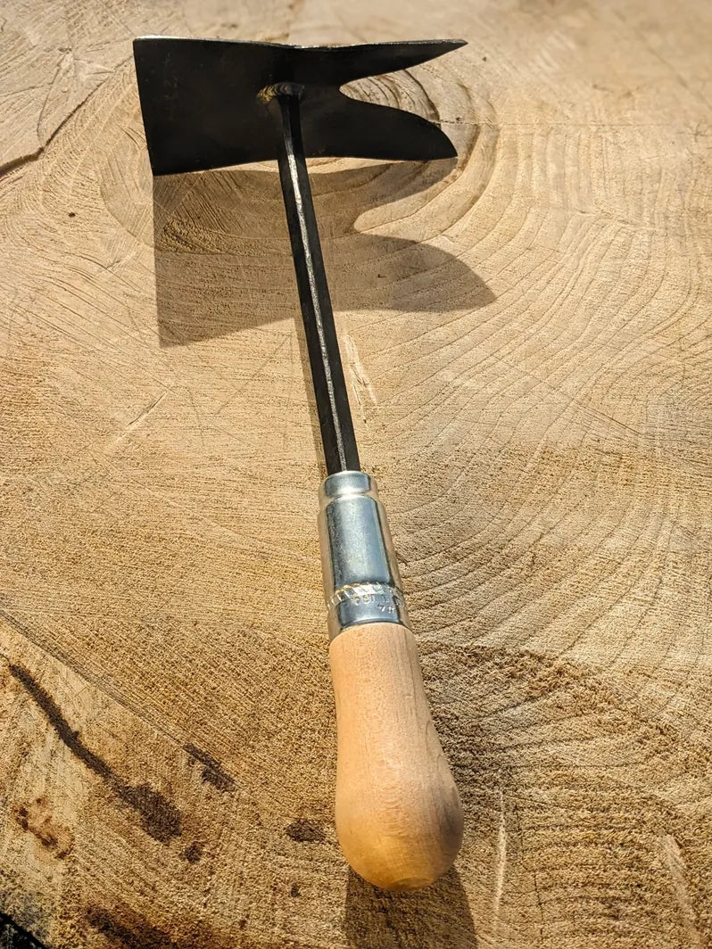 Grub Hoe, hand forged garden tool by Homestead Iron deep shadows on wooden background. 