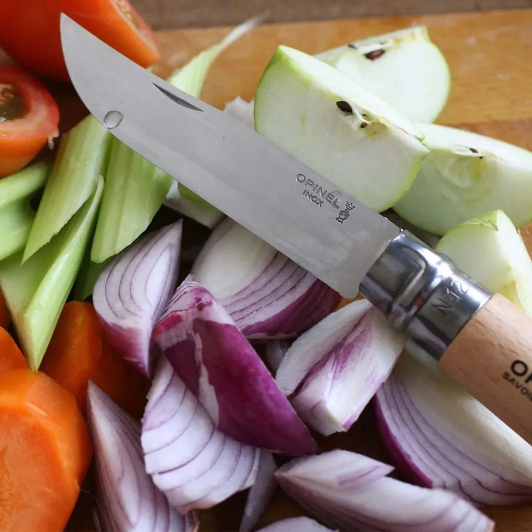 Opinel 12 stainless steel folding pocket knife by Homestead Iron with onions apples, celery, and carrots. 