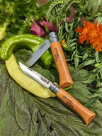 Two Opinel pocket knives on a leafy background with flowers