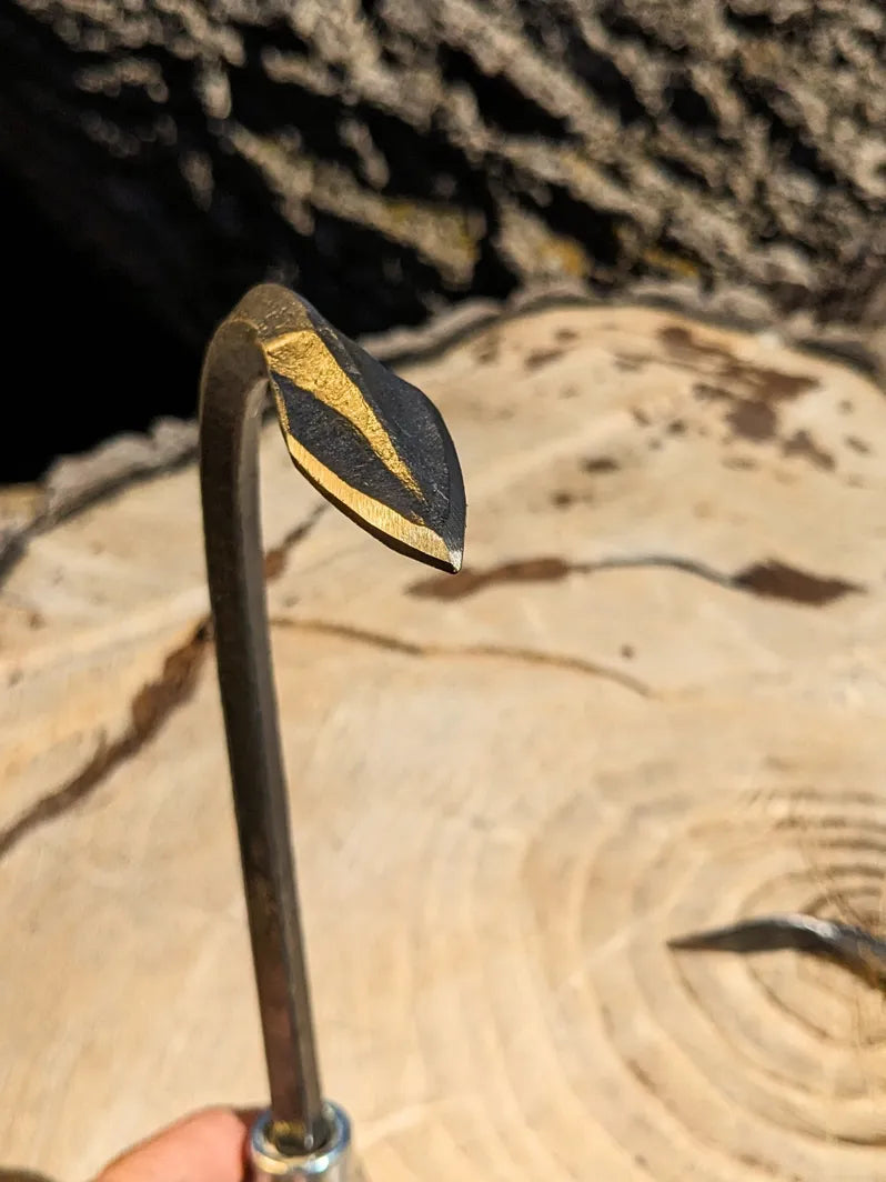 Single Tine Cultivator, Hand Forged Garden Tool by Homestead Iron bright sunlight on tool head with wooden background.