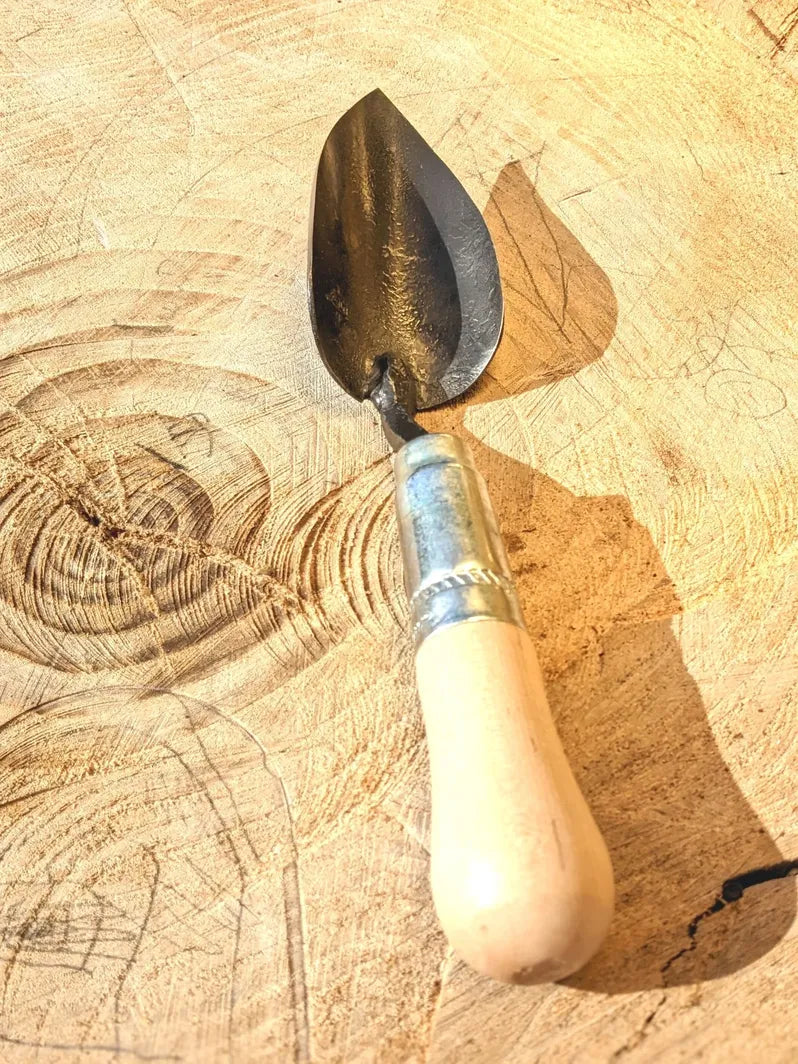 Small Trowel, Hand Forged Garden Tool Homestead Iron close up tool handle on wooden background