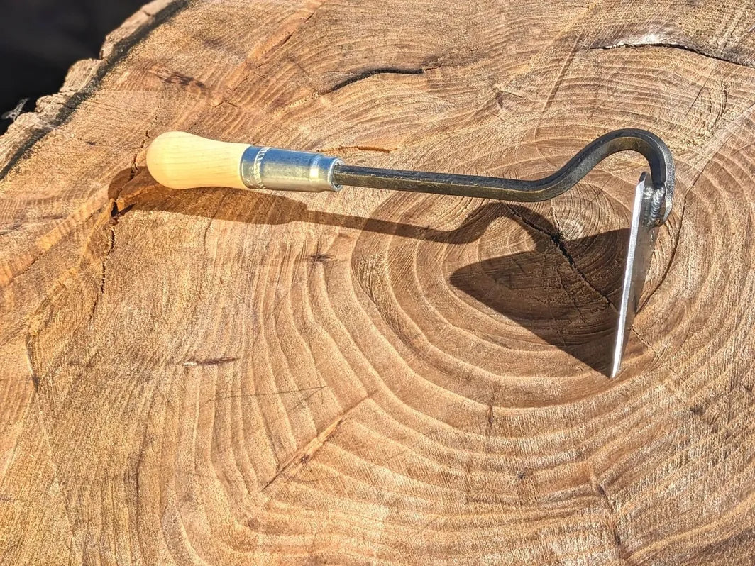 V-Hoe (Warren Hoe, Aggressive Hoe) Hand Forged Garden Tool Homestead Iron with tool head creating strong shadow on wooden background. 